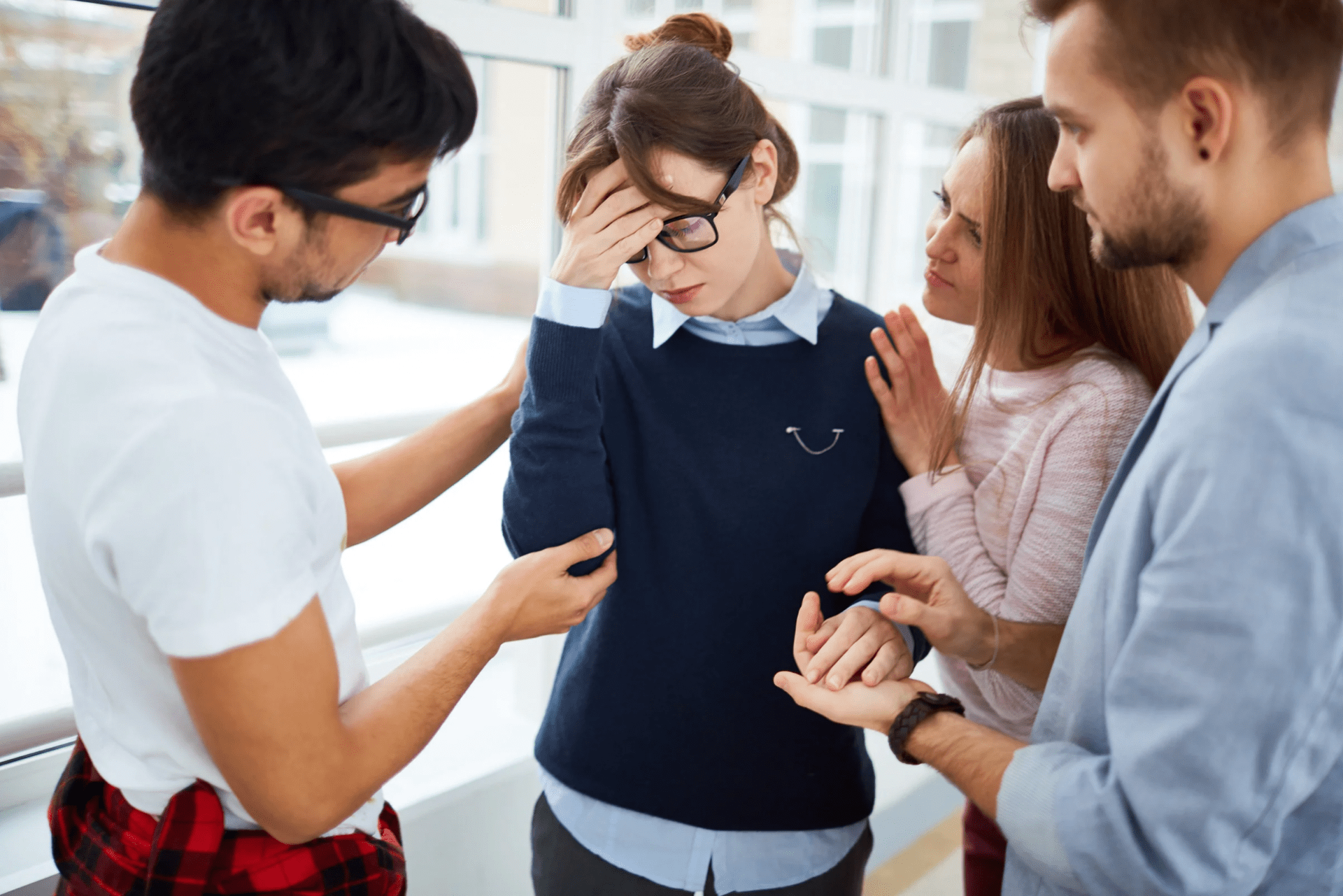 Un groupe de personnes réconfortant une femme qui semble accablée, illustrant le concept de l'hyperempathie.