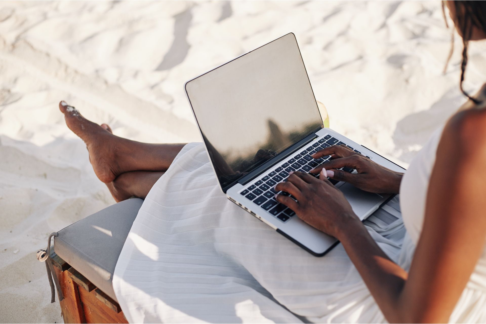 Personne travaillant sur un ordinateur portable sur la plage, illustrant la difficulté de se déconnecter du travail pendant les vacances