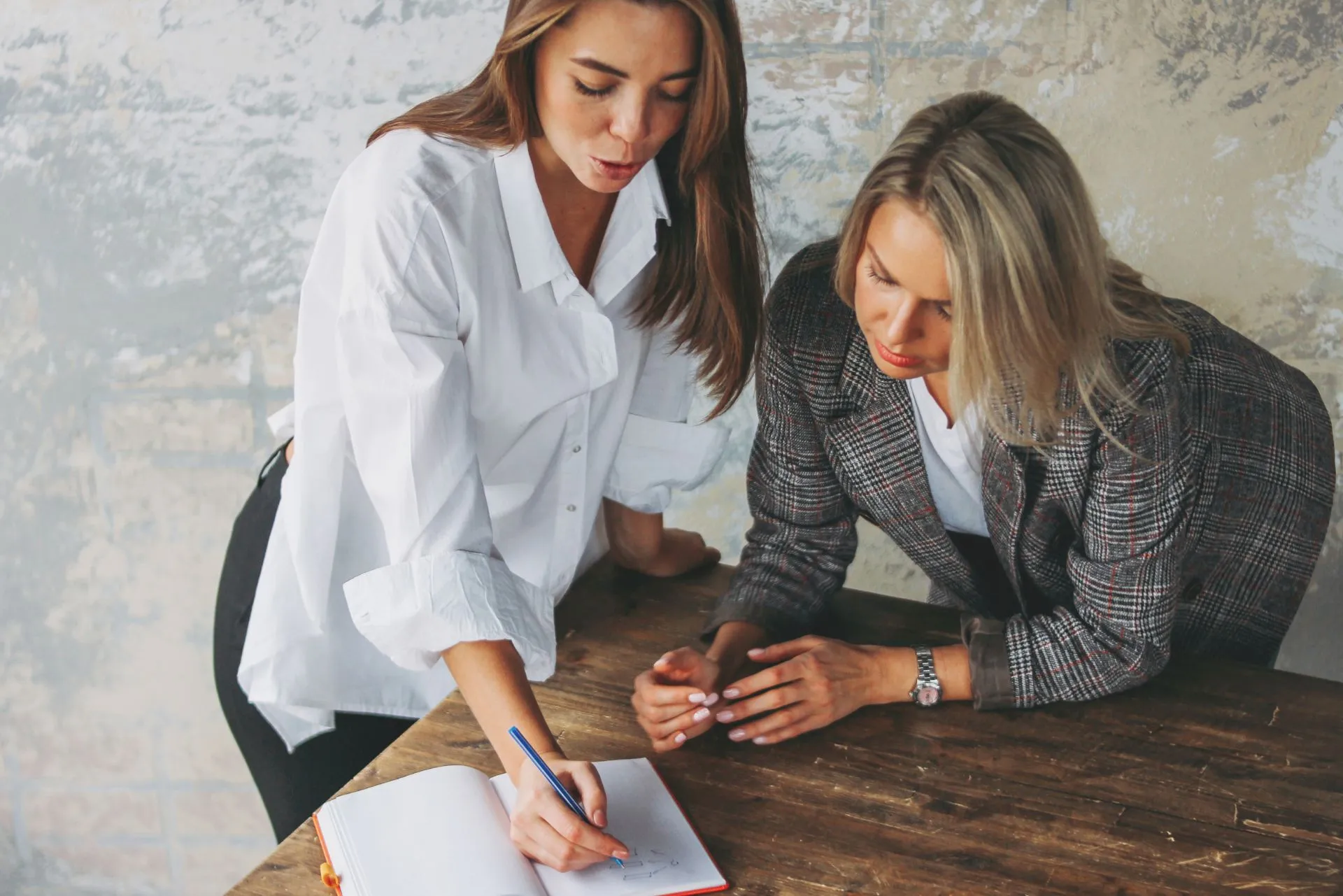 Deux femmes travaillant ensemble lors d'une séance de coaching professionnel à la rentrée, discutant de projets sur une table.