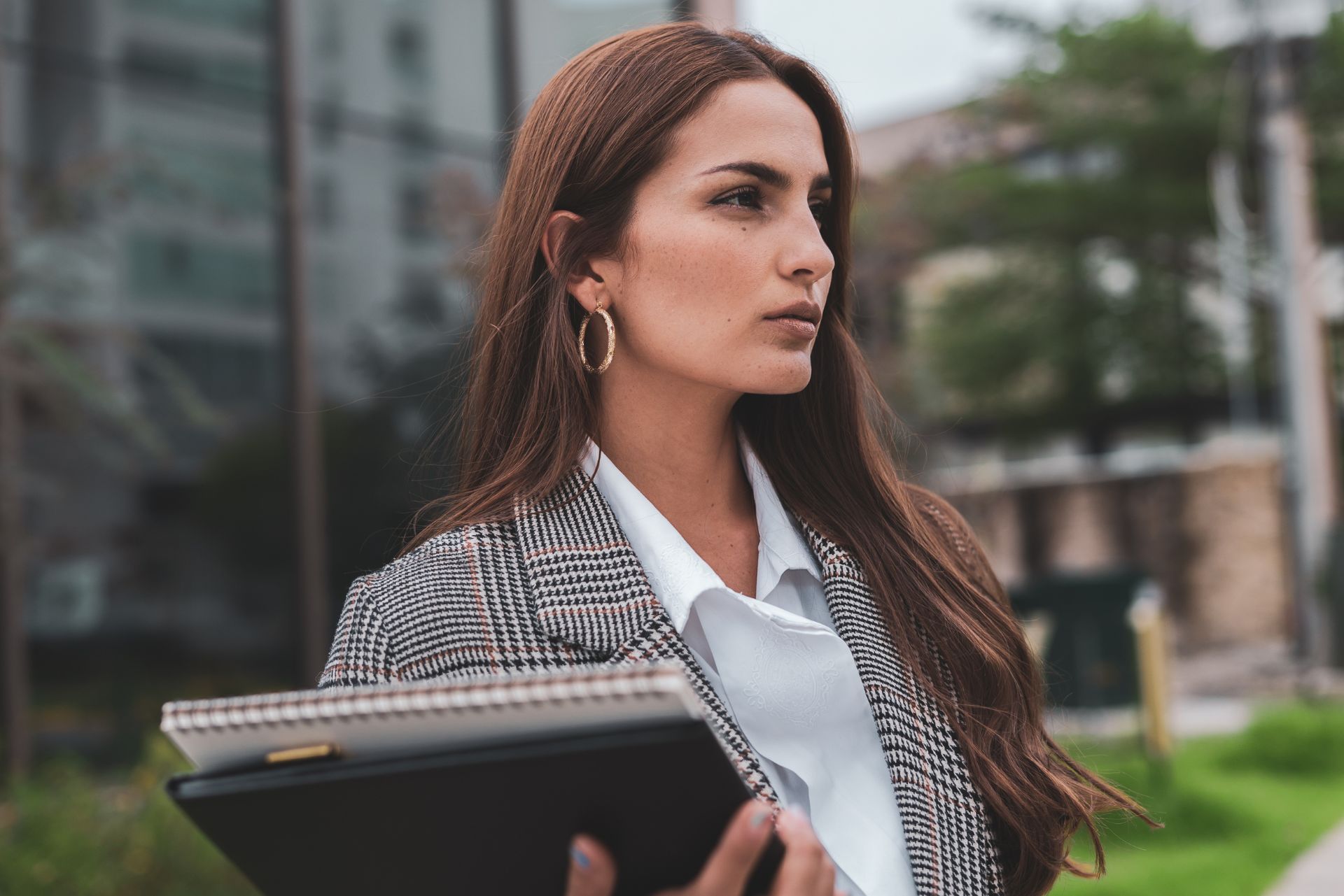 Femme marchant avec assurance dans un environnement urbain, portant un sac et un ordinateur portable, symbolisant la confiance en soi retrouvée