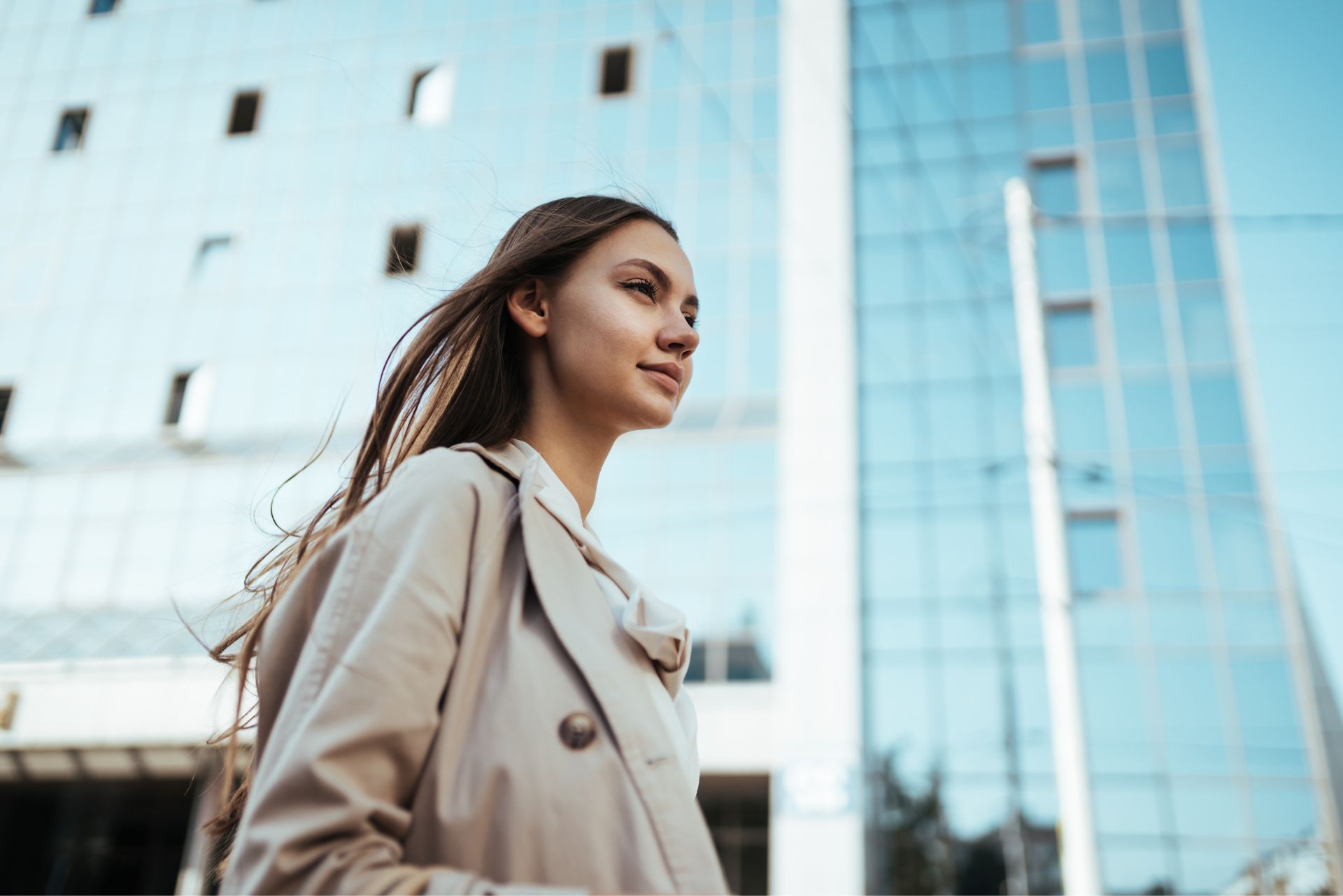 Prendre sa place : une femme avance avec assurance devant un immeuble moderne, symbole de confiance et de légitimité.