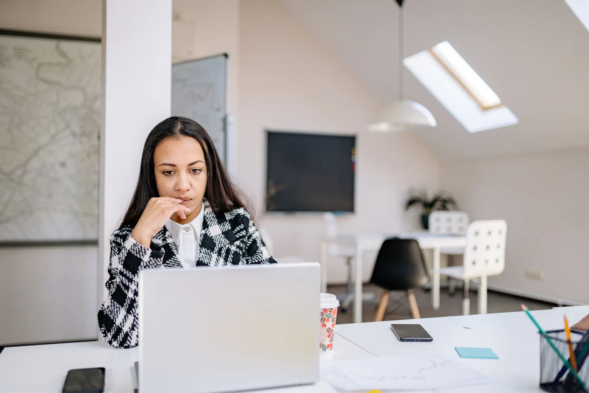 Femme pensive devant son ordinateur illustrant le syndrome de l'imposteur au travail et le doute professionnel