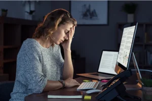 Femme stressée devant son ordinateur illustrant le stress au travail et le manque de confiance en soi